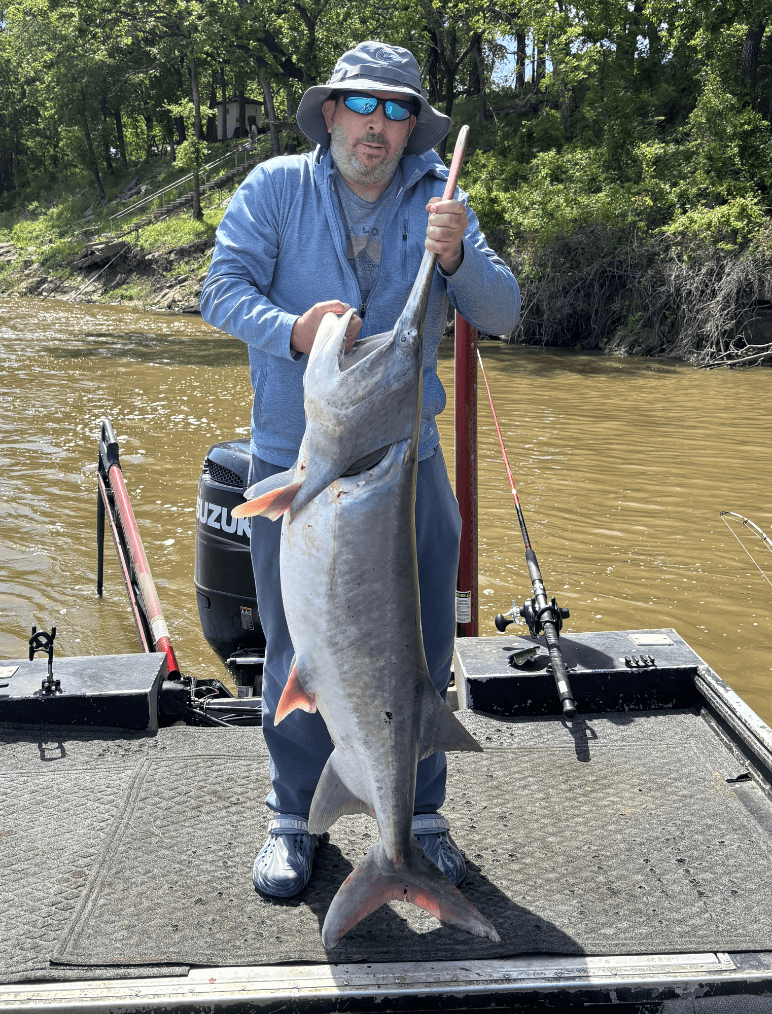 Andrew holding a large paddlefish on a fishing boat